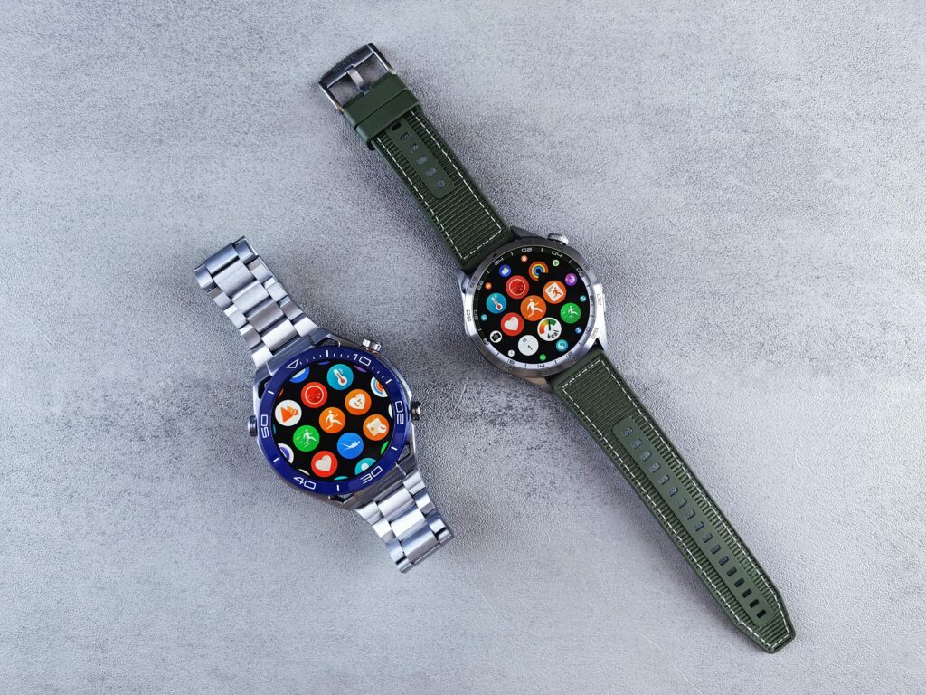 Two smart watches with colorful interfaces displayed on a sleek gray textured surface.